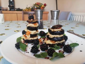 Photo of an aubergine, blackberry and mint dish on a dining table